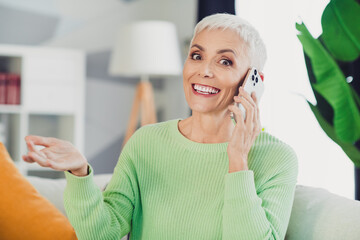 Charming senior woman with white hair using a smartphone at home while relaxing on a lovely and casual afternoon