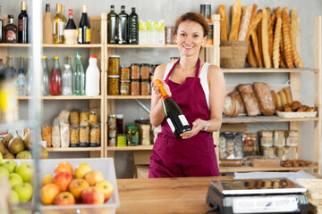Adult saleswoman offers to buy bottle of wine in grocery store