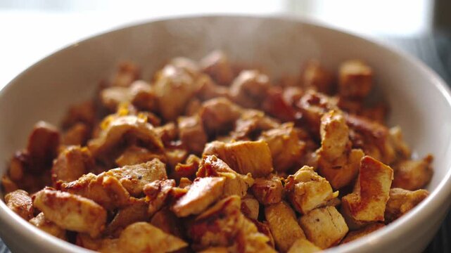 Juicy golden chicken breast cubes sizzling on a white plate, steam rising from freshly cooked diced meat. Perfectly seared protein for healthy meals, fitness diets or quick dinner recipes.