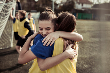 Teen girls hugging after soccer match on outdoor field