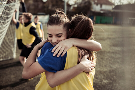Teen girls hugging after soccer match on outdoor field