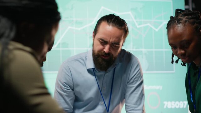 Diverse group of professionals review files and performance metrics, using projections and budgeting to align the company goals with stakeholder expectations for company progress. Camera B.