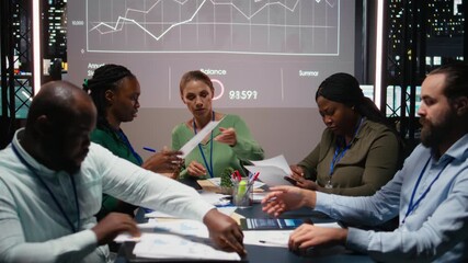 Close up of diverse business team meeting after hours for visual data reports, reviewing infographics and projections while sharing files to establish finance objectives. Business intel. Camera A. - Powered by Adobe