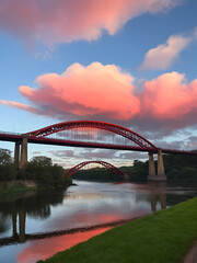 Naklejka premium Bridge over the river at noon with red clouds in the sky