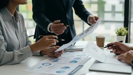 Business team collaborating on financial reports in a modern office setting with charts and coffee - Powered by Adobe