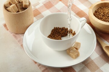 Pouring hot water into cup with instant coffee at light table, closeup