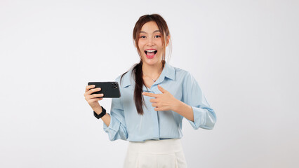 Happy young excited Asian woman laughing, handholding a phone and pointing. She smiles, showing a promotion on her mobile phone device. isolated studio white background