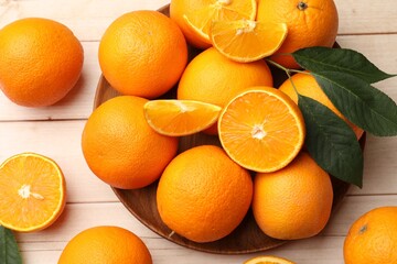 Fresh ripe oranges and leaves on light wooden table, flat lay