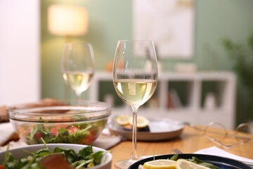 Tasty food and glasses of white wine on table indoors, closeup