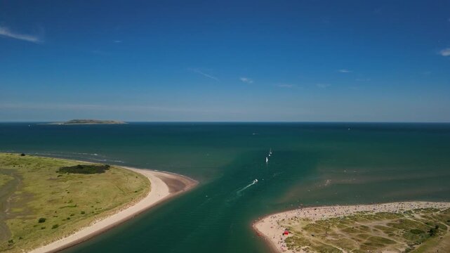 Drone zoom out with view of Malahide beach, Lambay Island and ships sailing out to sea