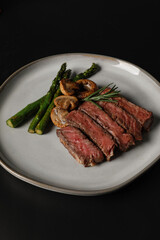 Medium-rare steak served with grilled asparagus and sautéed mushrooms, plated elegantly on a ceramic dish.
