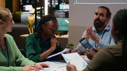 Business people prepare for a pitch by studying financial data on files reports inside the boardroom after hours. Exchanging insight and delivering forecasting updates for management. Camera B. - Powered by Adobe