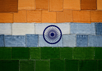 The national flag of India creatively assembled from a patchwork of orange, white, and green denim fabric pieces.