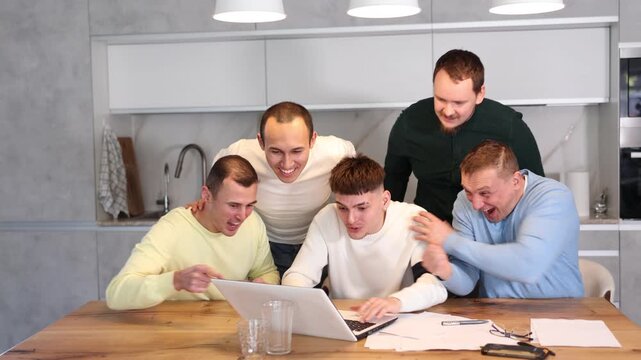 Group of men watching sports match online on laptop during friendly meeting with beer at home, excitedly celebrating winning score in game 