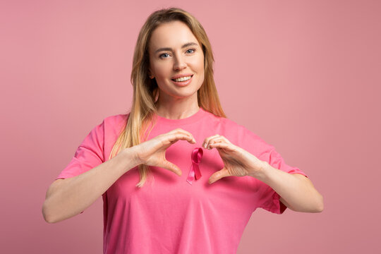 Woman making heart shape with hands supporting breast cancer awareness