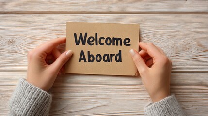 Hands Holding Welcome Aboard Card on Wooden Background