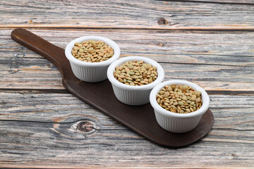 Green lentils in wooden bowl on wooden table background. Top view, copy space. Flat lay.