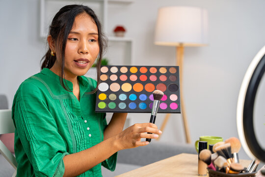 Beauty influencer showing makeup palette and brush during livestream