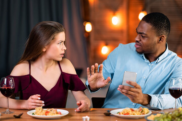 Annoyed Woman Arguing With Black Boyfriend In Restaurant, Blaming Him For Smartphone Addiction, Man Trying To Protect Himself. Young Interracial Couple Having Problems In Relationship, Free Space