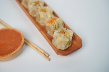 Steamed Dumplings with Spicy Sauce on Wooden Plate