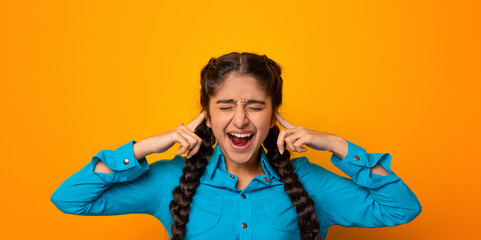 I Don't Want To Hear It. Portrait of irritated indian woman covering her ears, plugging with...