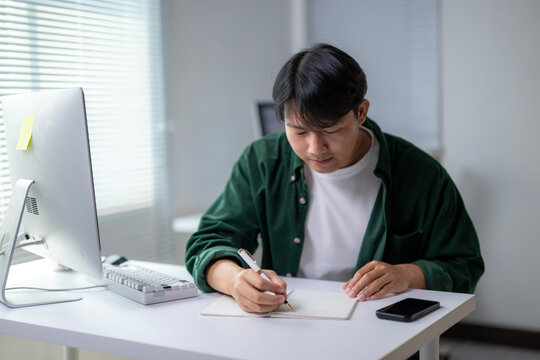 A man is sitting at a desk with a notebook and a pen