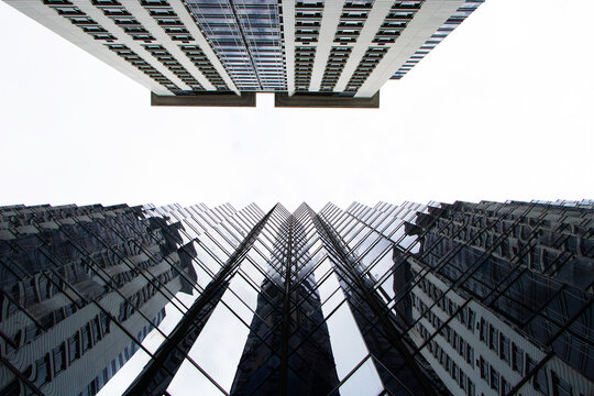 Gap between bottom of ้high-rise building top. Texture background abstract. Blue sky with white clouds and bright sunlight shining through. Large building structure in business district in big city.