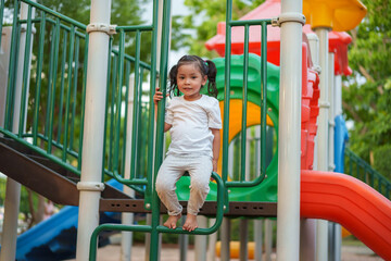 Obraz premium happy toddler girl playing and climbing on outdoor playground at park