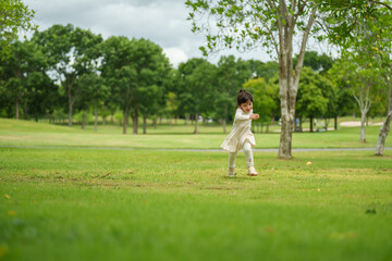 happy toddler girl in white dress running on green grass field