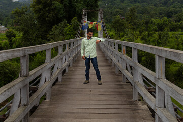 Man checking time on wooden bridge in himachal countryside