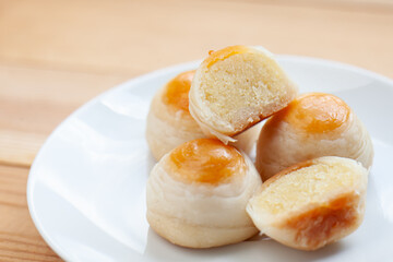 Chinese pastry or mooncake on white plate on wooden table. close up delicious Cantonese moon cake.