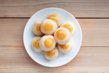 Chinese pastry or mooncake on white plate on wooden table.Top view food. Afternoon tea, holiday celebration serving.
