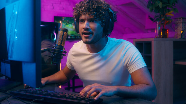 Emotional worried American Indian Arabian Muslim man streamer playing game computer competition male guy happy player gamer neon home cyber sport online winning victory blogger celebrate gaming addict