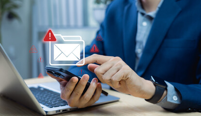 Businessman using smartphone with warning symbol for email hacking, spam, and cyber threats. Concept of cybersecurity, spyware, network attacks, and digital crime prevention.
