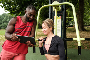 Personal trainer showing workout routine on tablet to woman in a park