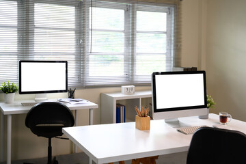 Bright workspace with computer monitors featuring blank screens and natural lighting