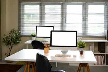 Fototapeta premium Modern workspace with blank desktop computers for advertising or branding mockups