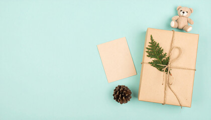 Gift Box and Teddy Bear: A beautifully arranged gift box tied with natural twine, adorned with a fern, sits alongside a blank card and a cuddly teddy bear, all set against a minimalist backdrop.