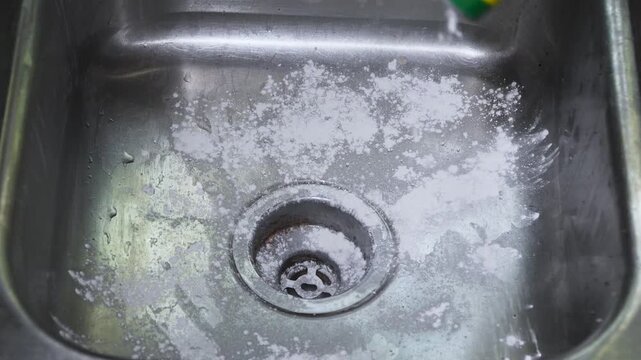 Cleaning a dirty, metal kitchen sink with powdered bleach