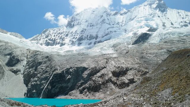 Slow aerial approach reveals the brilliant turquoise Laguna 69, then tilts up to showcase the majestic snow-capped Cordillera Blanca mountains in Huascar&aacute;n National Park, Peru.