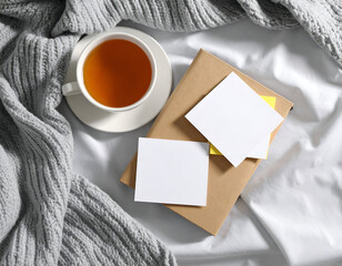 A comforting flat lay captures a serene morning with a warm teacup, soft knitted blanket, and blank sticky notes, ideal for mindful planning or a peaceful study session.