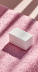 White rectangular object on a pink textured surface, bathed in sunlight