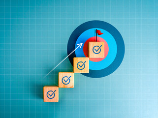 Roadmap to success, business direction, goal achievement, leadership concept. Arrow upward to red flag on top of wooden steps with checkmark signs, as growth graph on big target icon, blue background.