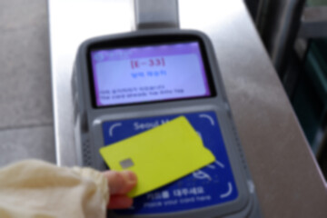 A blurry image of a transportation card being scanned at a subway reader.
