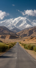 Naklejka premium Asphalt Road Winding Towards Snow Capped Mountains Under Clear Blue Sky