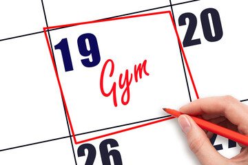 19th day of the month. Hand writing Gym reminder and drawing red frame on calendar with red pen on...