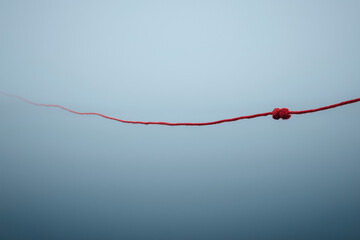 Minimalist red string floating gently in a soft foggy blue environment symbolizing emotional distance or fragile connection clean and symbolic