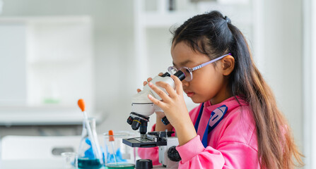 girl is looking through microscope