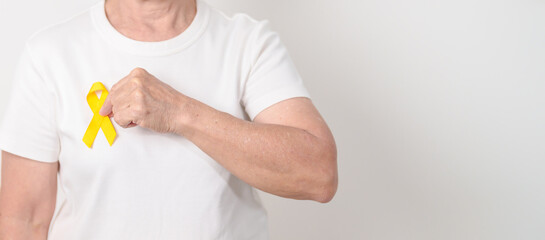 Elderly with Yellow Ribbon for concept of yellow September, Suicide prevention day, Childhood, Pediatric, bone and bladder cancer Awareness month, support survivor. Healthcare and World Cancer day