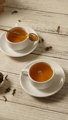 cup of tea, tea being poured into a transparent and white tea cup, teapot and tea cup with floral motif, darmkmood tea photo display